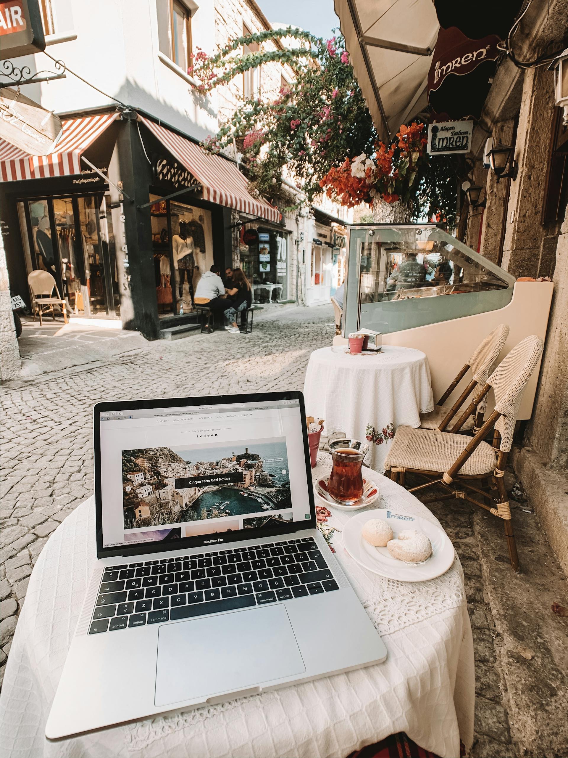 Enjoy my blogs! 1 Laptop on table at a charming café in cobblestoned streets of Alaçatı, İzmir.